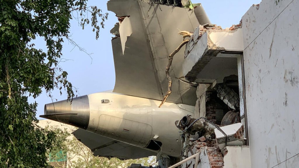 Équipe de secours sur le site du Air India crash Ahmedabad, avec des débris de l’avion et des fumées visibles.